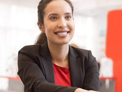 woman in red shirt black jacket shaking hands red wall to the right