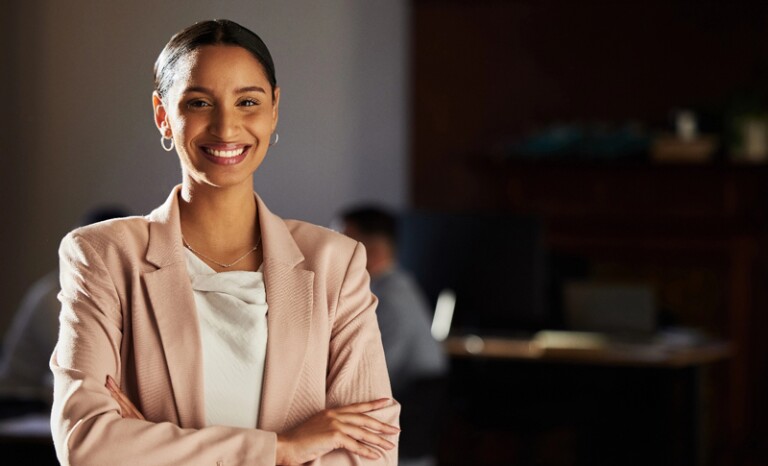 Woman in office smiling with arms crossed