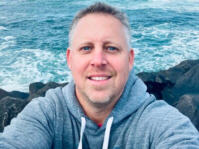 Brian Gordon, KU Professor, standing on rocks next to the ocean.