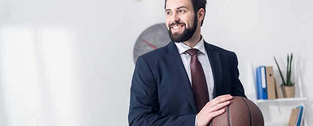 businessman with sports management job holding basketball ball in office