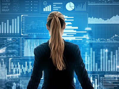 A businesswoman in a suit reviews business analyst job outlook data on a large screen.