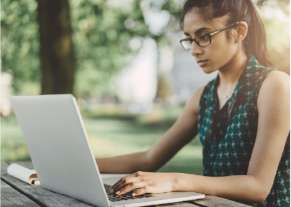 young lady with glasses and floral top working on laptop