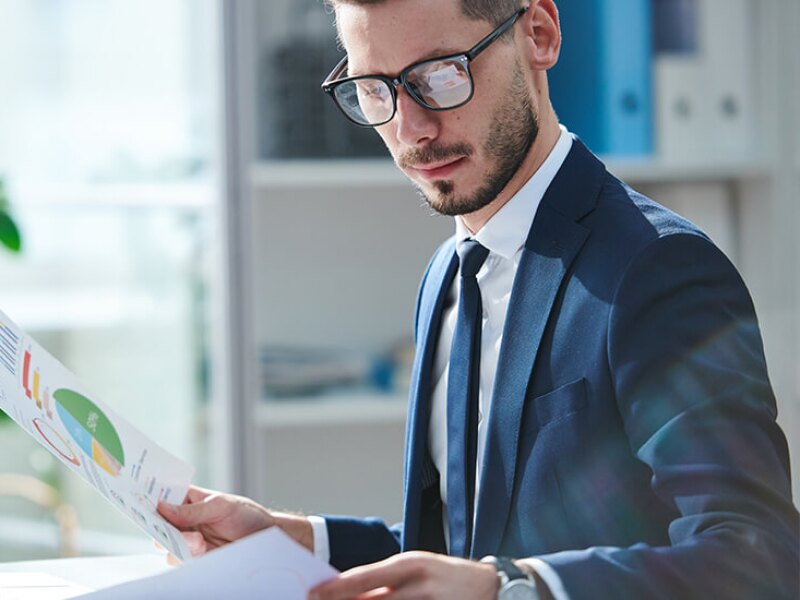 Man in suit with laptop computer studying charts