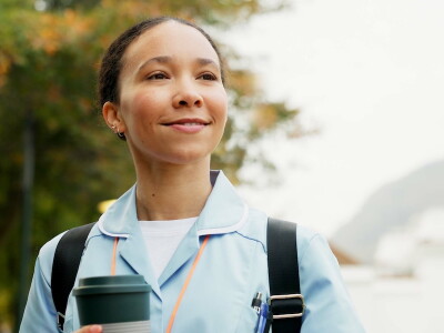 An allied health professional smiles while standing outside her place of employment