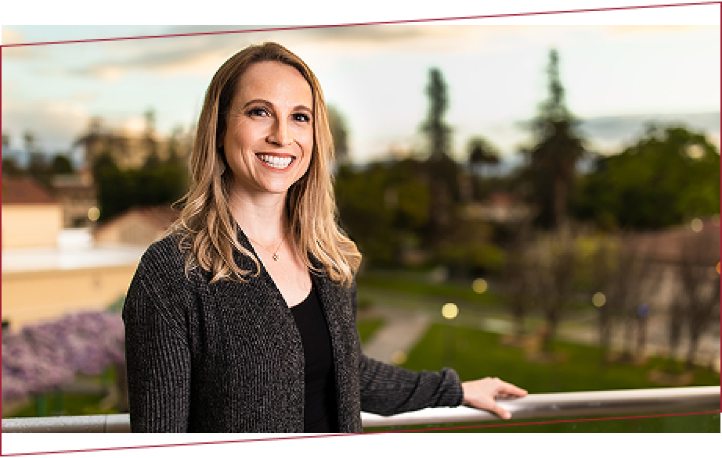 Smiling female SCU student on a balcony with the campus in the background