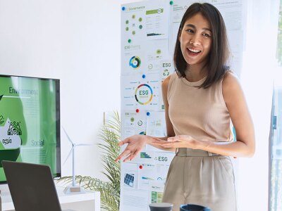 A woman presents a business ethics practice with ESG information to colleagues in a modern office setting.