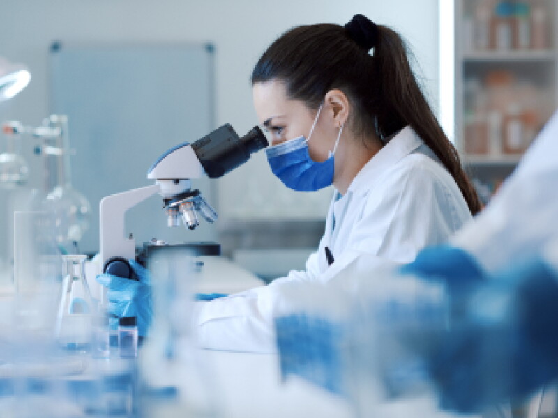 Close-up of a female CWRU biomedical engineering student looking through a microscope.