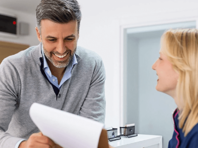 Man and woman smiling at desk and looking at paperwork