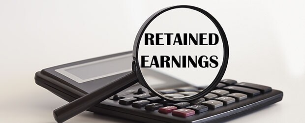 Focused on Retained Earnings concept. Magnifier glass with text on calculator.