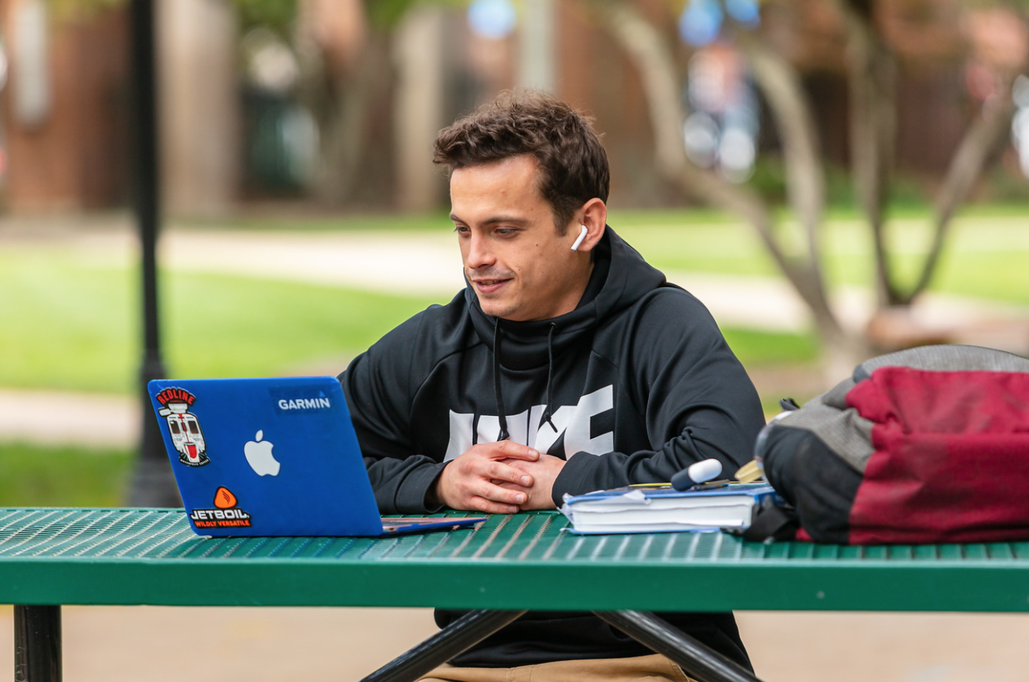 Student on a blue Macbook laptop in a courtyard