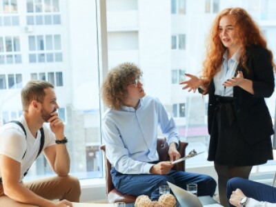 A group of young professionals sit together and discuss a chart