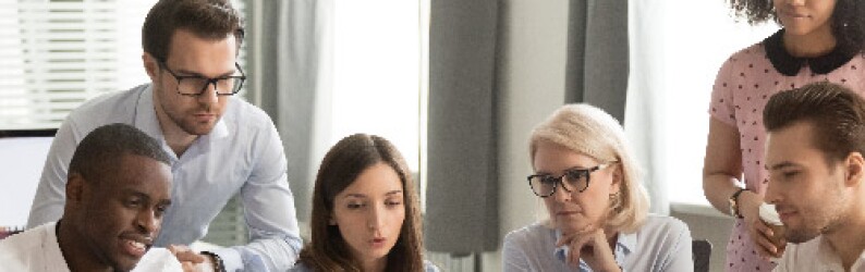 Group of Employees Gathered Around Laptop Screen