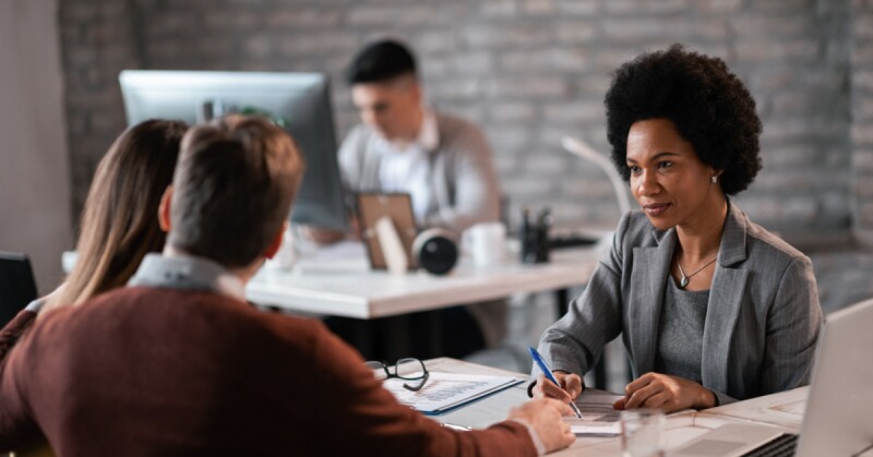 Woman in office takes notes as she actively listens to clients.