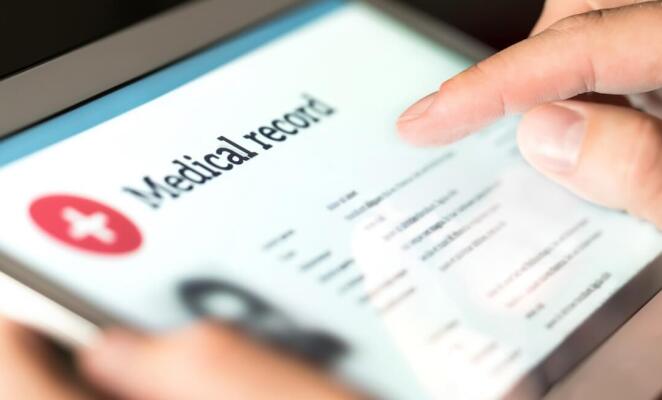 Close up of hands using tablet displaying medical records
