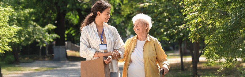 Young African-American female social worker walking with elderly woman outdoors