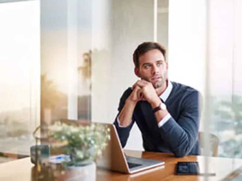 Young man contemplating career while working on laptop.