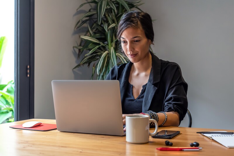 Young woman working online at home with laptop and documents