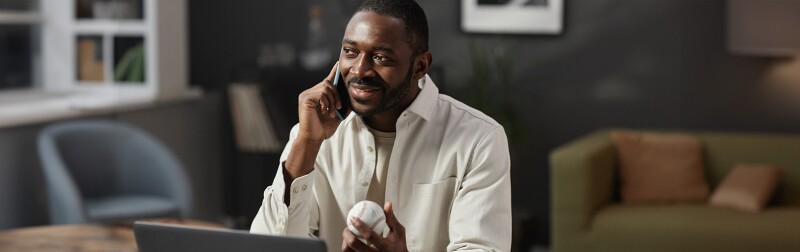 Man speaking on the phone in his office holding baseball