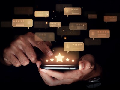 Hand of man using smartphone with five star review for a brand