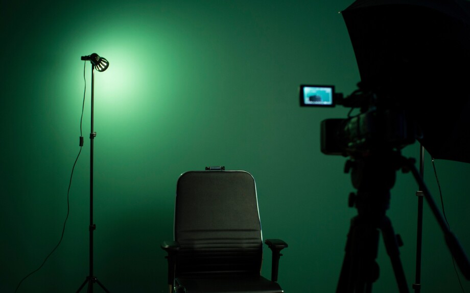 Green screen background and a black chair in a production studio.