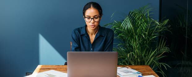 focused woman working on laptop at her desk