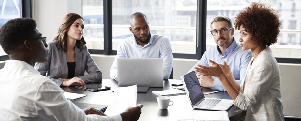 Woman speaking to team around conference table