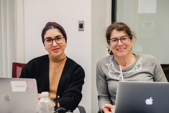 two students on laptops smiling at camera