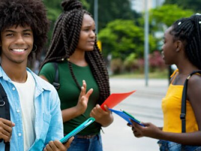 Man smiling with backpack and women talking outdoors