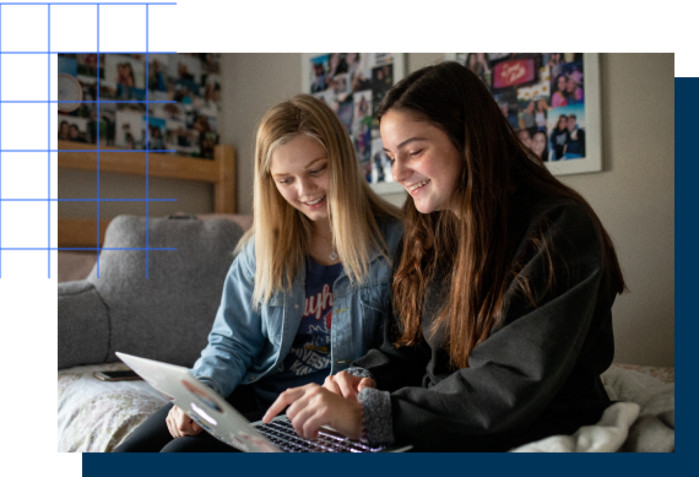 Two female KU students look at a laptop together while in a dorm room.