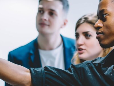 Diverse team of skilled buisness professionals together solving task writing down information on sticky notes.
