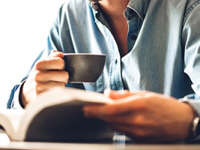 Man drinking coffee and reading one of the best sports management books for your career