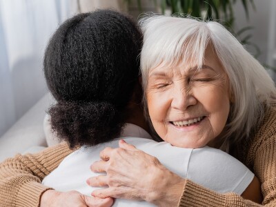 Smiling senior client hugs her social worker during a session