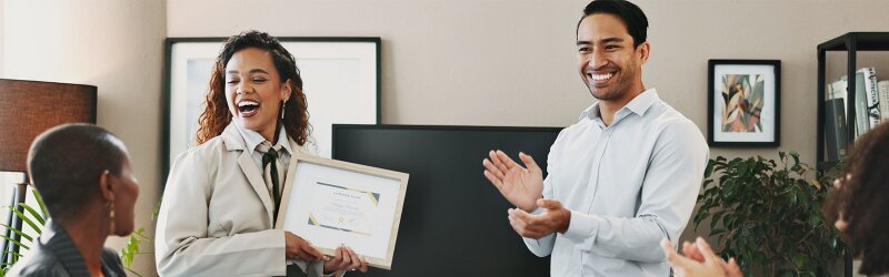A joyful businesswoman is awarded the "Leadership Award" certificate in an office to show appreciation from the company.