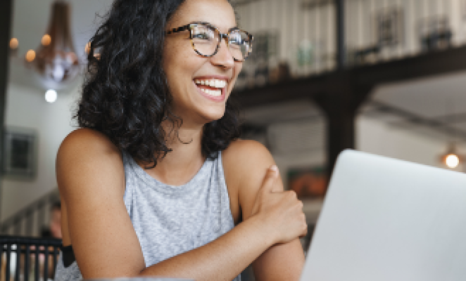 smiling student with glasses sitting in front of laptop