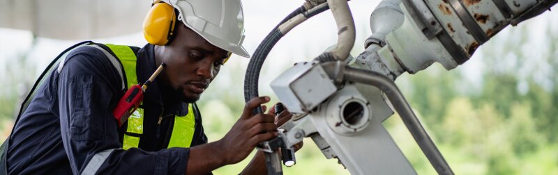 Aircraft maintenance engineer inspecting airplane engine with safety equipment and tools.