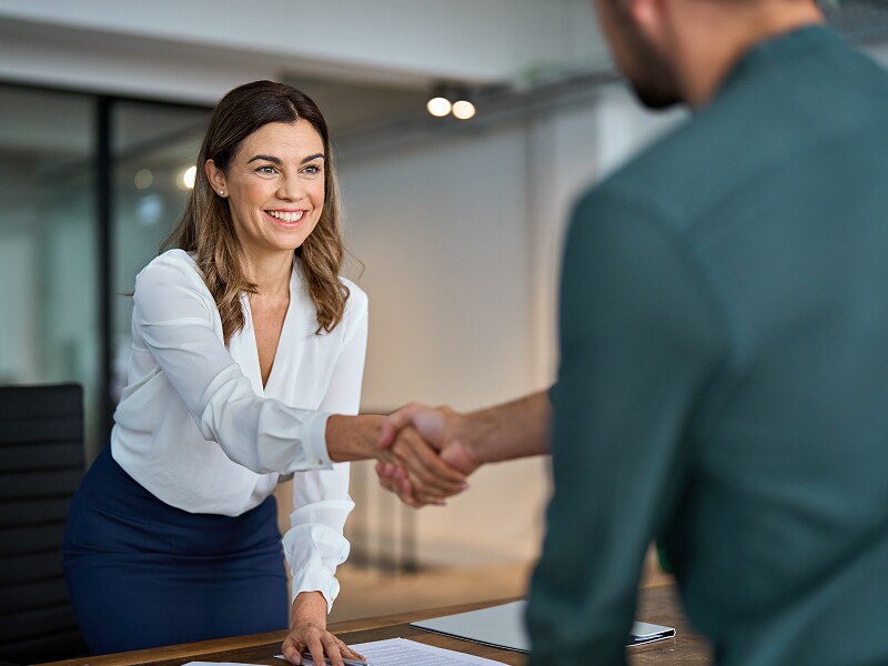 Professional woman and man shaking hands in an office