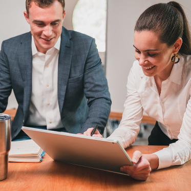 man and woman at table looking at laptop