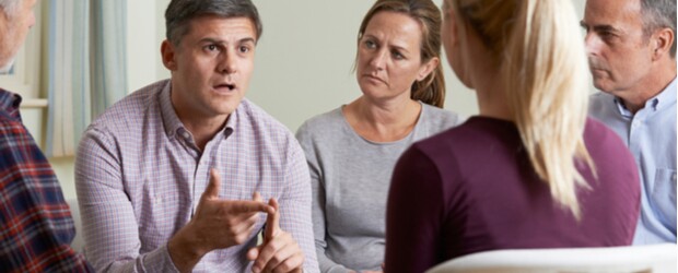 Members Of Support Group Sitting In Chairs Having Meeting