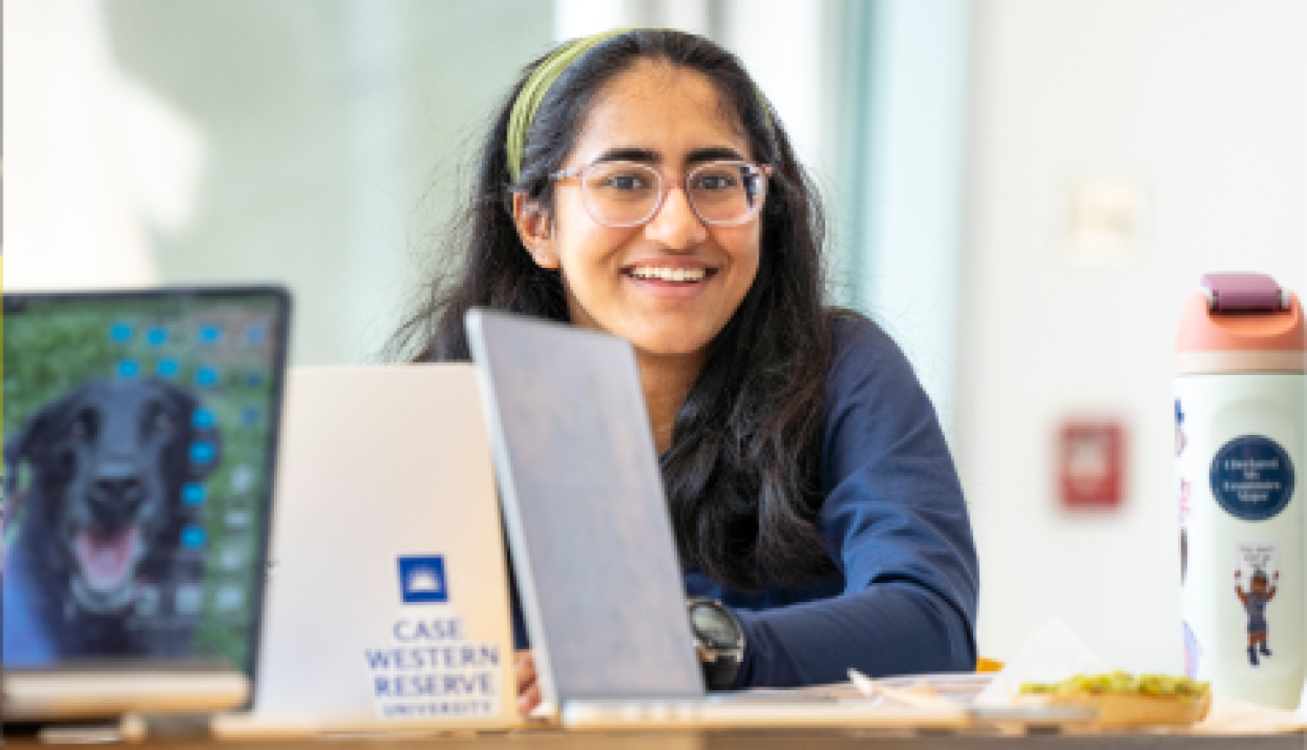Close-up of a smiling female CWRU student working on laptop.