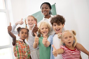 Children showing thumbs up while feeling amazing after a lesson from their teacher.