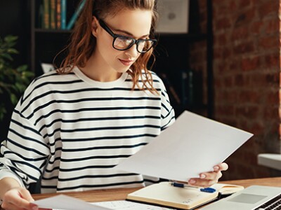 woman-in-black-and-white-stripe-sweater-works-on-resume-for-business-school
