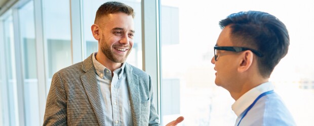 two men having a conversation next to a window