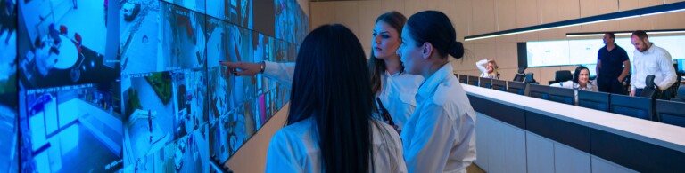 Three professionals review security footage panels