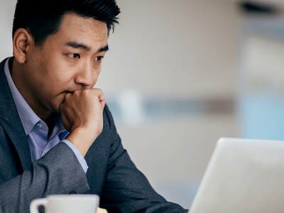 Businessman sitting at workplace desk near laptop thinking about a decision