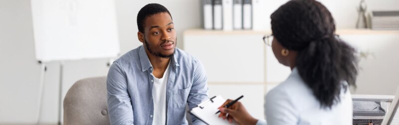A young black man having session with professional psychologist at mental health clinic.