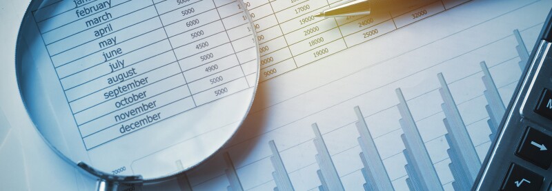 Financial documents with calculator, pen and magnifying glass