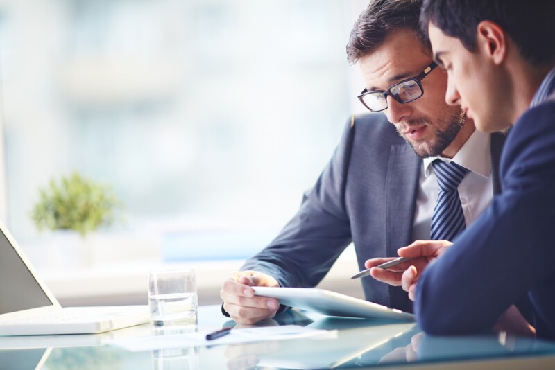 Two men looking at a tablet and discussing sport management
