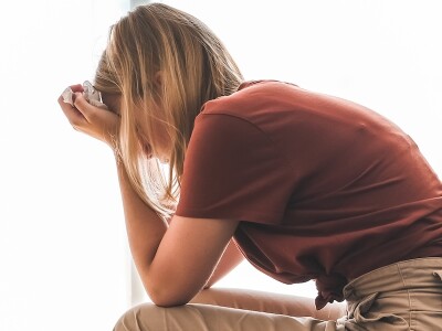 In a counselor's office, an exhausted woman sits with her head in her hands.