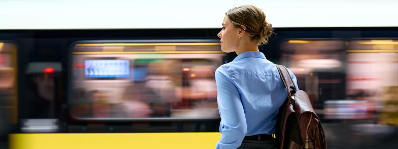 Professional woman at metro platform with moving train