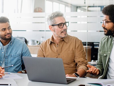 A team engaged in a strategic meeting, with a senior colleague leading discussion.